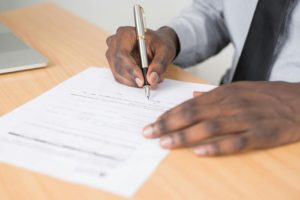 Close-up of a businessman signing a contract at an office desk